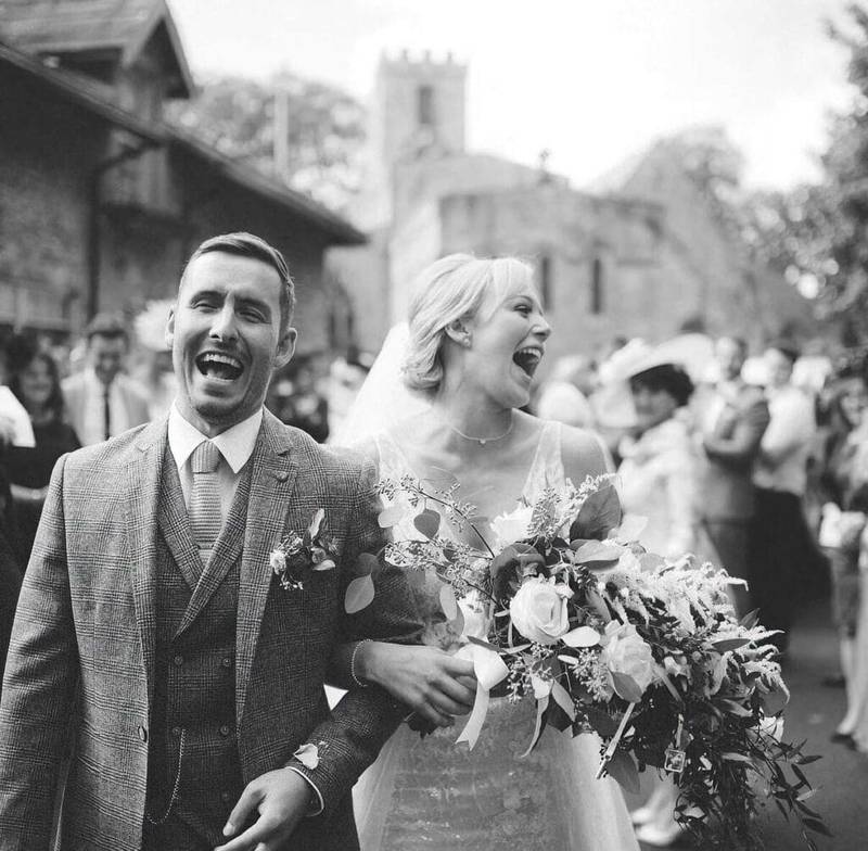 4 yorkshire wedding barn photographer - couple smiling as they leave church - black and white photograph
