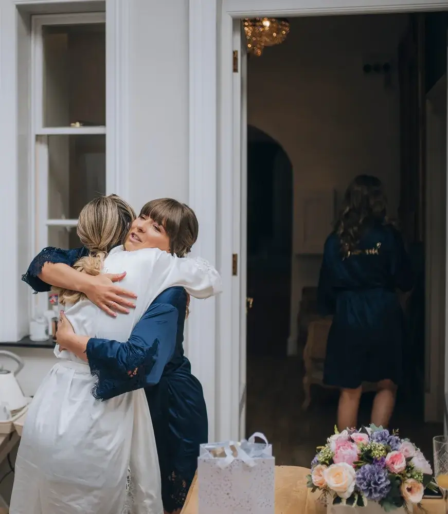 wedding photos bride & bridesmaid exchanging gifts whilst crying and hugging