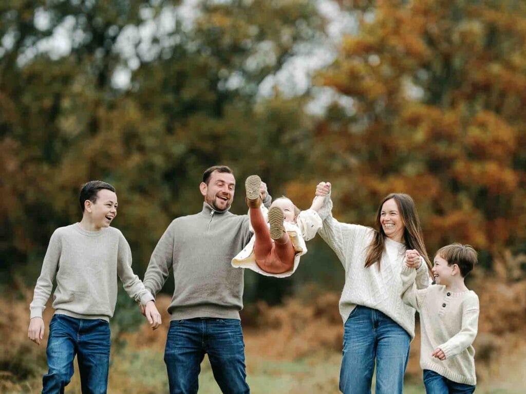 family of 5 laughing playing in the autumn park