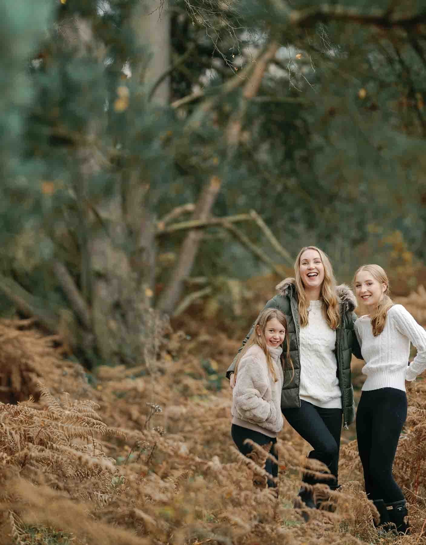 mother and 2 ung yodaughters lsughng in autumnal park setting