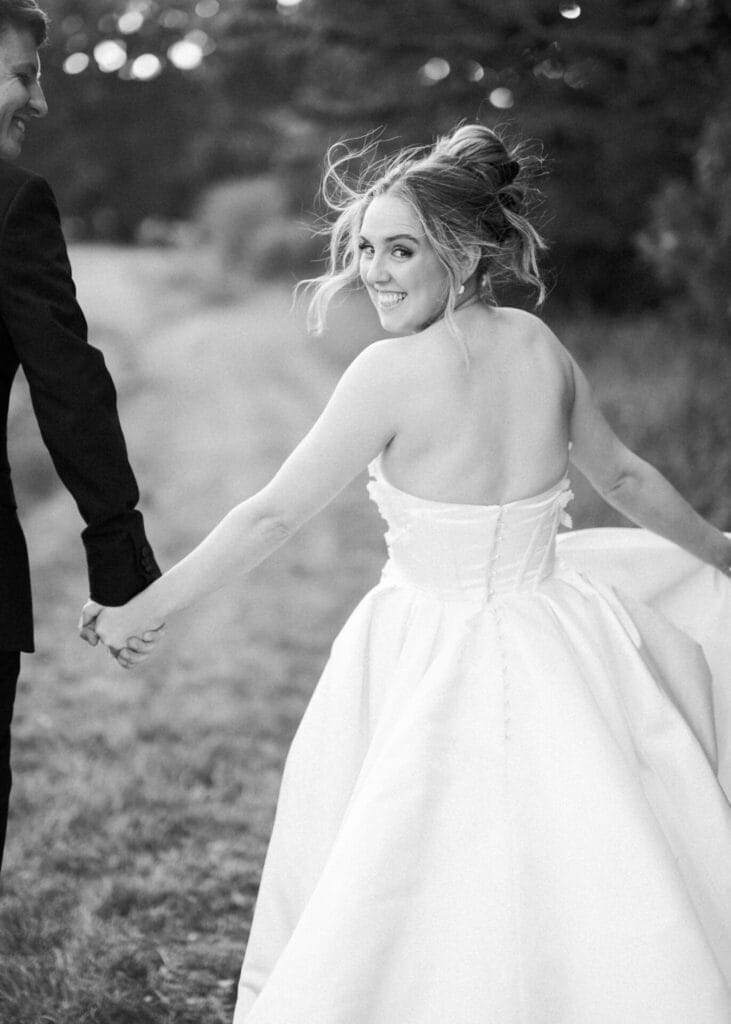 bride and d groom running looking back at the camera towards their Norwood Park wedding photographer